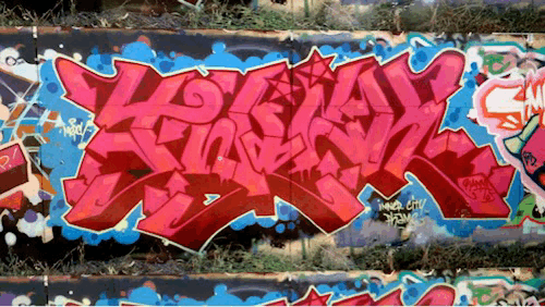 An animated GIF. Starting with a closeup of a graffiti piece by TWICK, we zoom out slowly to reveal that it's just one slice of a timelapse stack showing all the changes that have happened along a much larger wall over a span of years.